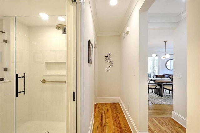 corridor with baseboards, light wood finished floors, and crown molding