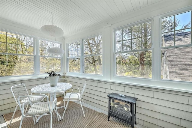 sunroom featuring a wood stove, a wealth of natural light, and carpet