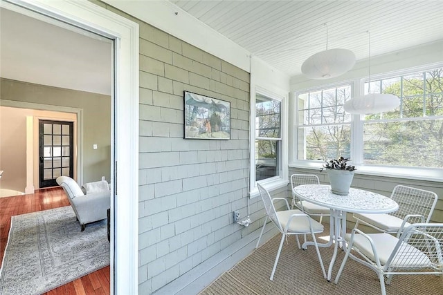 sunroom featuring tile walls and wood finished floors