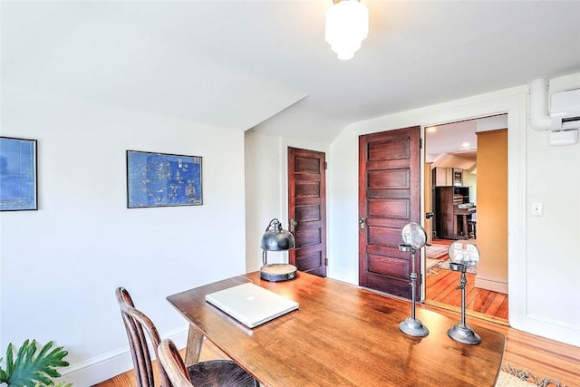 office area featuring a wall mounted AC, baseboards, and wood finished floors