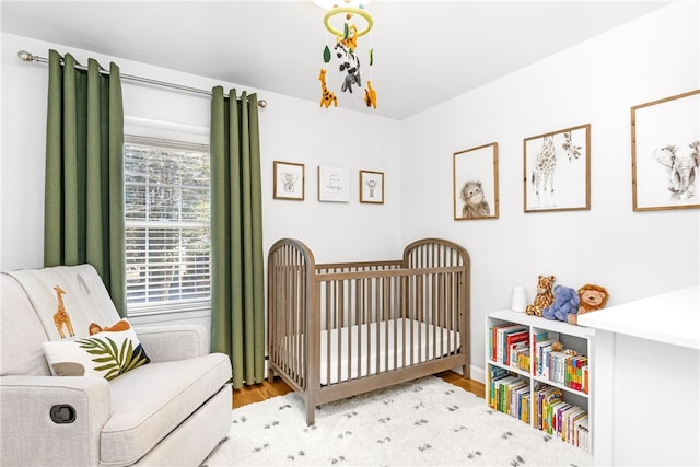 bedroom featuring a crib and wood finished floors
