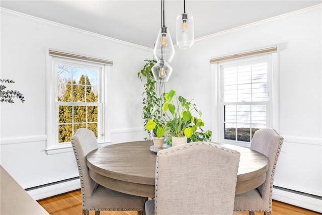 dining space featuring a baseboard heating unit, light wood-type flooring, and crown molding