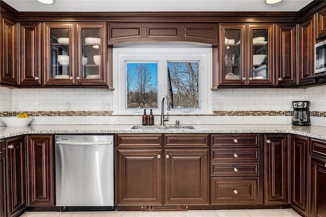 kitchen featuring glass insert cabinets, dark brown cabinets, a sink, appliances with stainless steel finishes, and tasteful backsplash