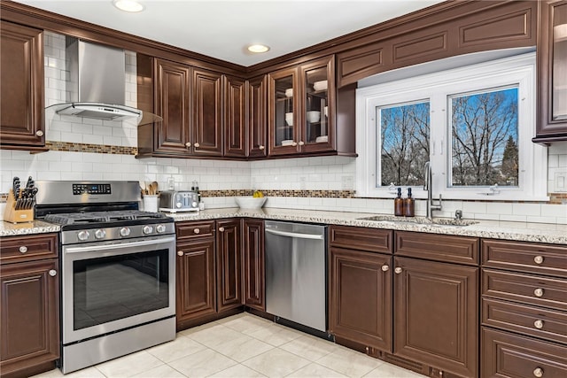 kitchen with a sink, dark brown cabinetry, stainless steel appliances, and wall chimney exhaust hood