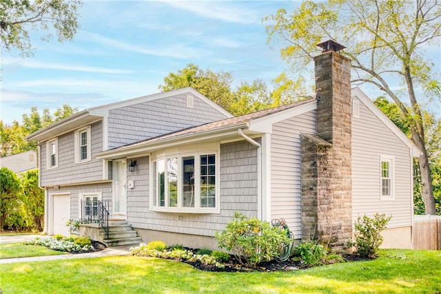 split level home with a chimney, a front lawn, and a garage