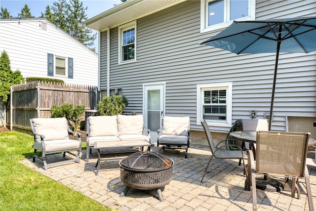 view of patio with an outdoor living space with a fire pit and fence