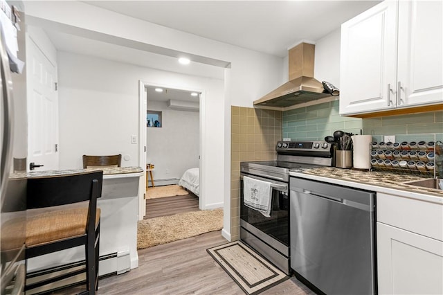 193 Harrison St, Pawtucket, RI 02860 - kitchen featuring stainless steel appliances, wall chimney range hood, baseboard heating, white cabinets, and light wood-style floors