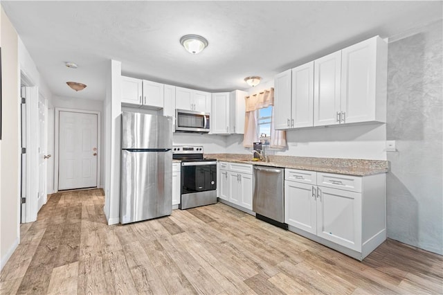 193 Harrison St, Pawtucket, RI 02860 - kitchen featuring light wood-type flooring, light stone countertops, white cabinets, and appliances with stainless steel finishes