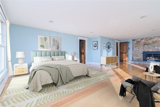 bedroom featuring a fireplace, baseboards, and wood finished floors