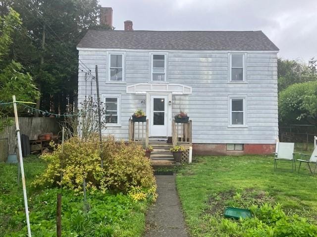 colonial home with a chimney, a front lawn, and fence