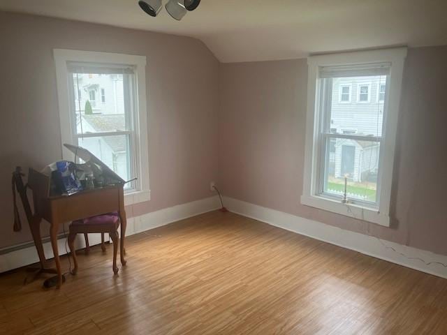 additional living space featuring a wealth of natural light, light wood-style floors, and vaulted ceiling
