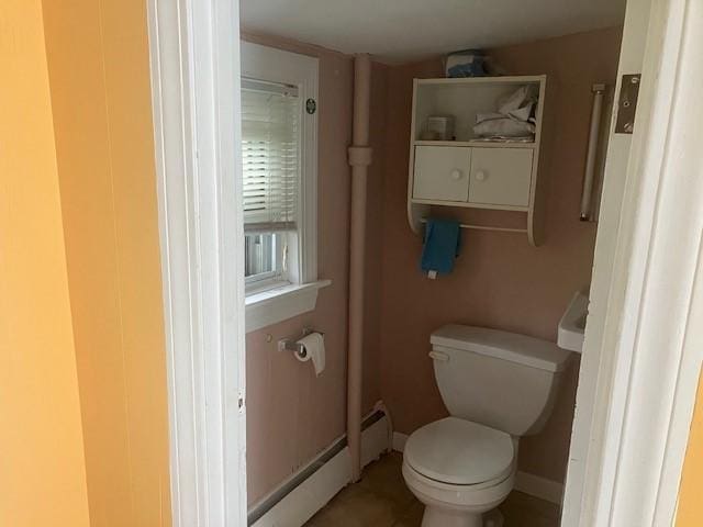 bathroom featuring toilet, baseboards, and a baseboard heating unit