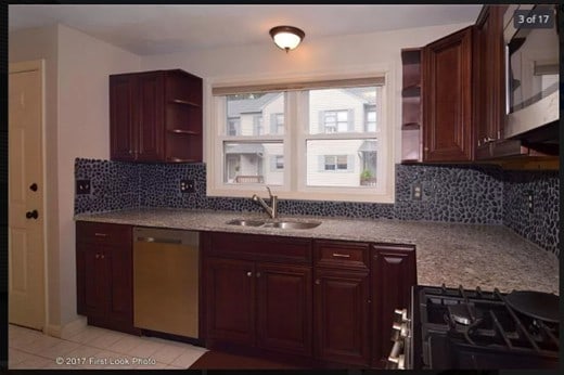 kitchen with a sink, open shelves, stainless steel dishwasher, light stone countertops, and backsplash