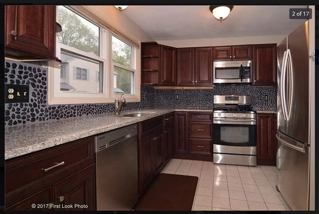 kitchen featuring a sink, stainless steel appliances, tasteful backsplash, light countertops, and light tile patterned floors