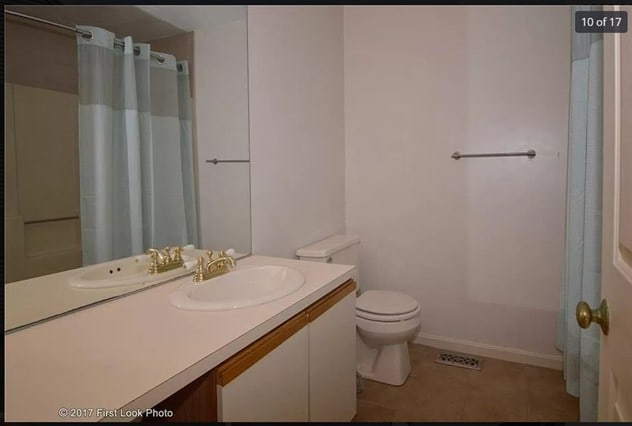 bathroom with toilet, baseboards, curtained shower, tile patterned flooring, and vanity