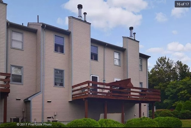 rear view of house with central AC unit, a chimney, and a deck