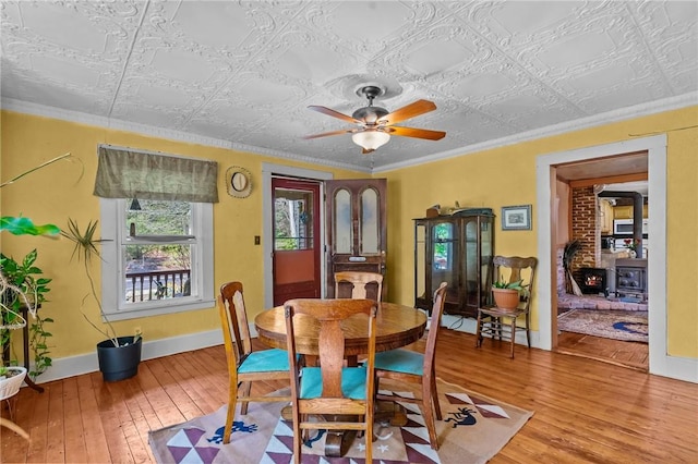 48 Highview Ave, Hopkinton, RI 02832 - dining room featuring hardwood / wood-style flooring, a wood stove, baseboards, an ornate ceiling, and ornamental molding