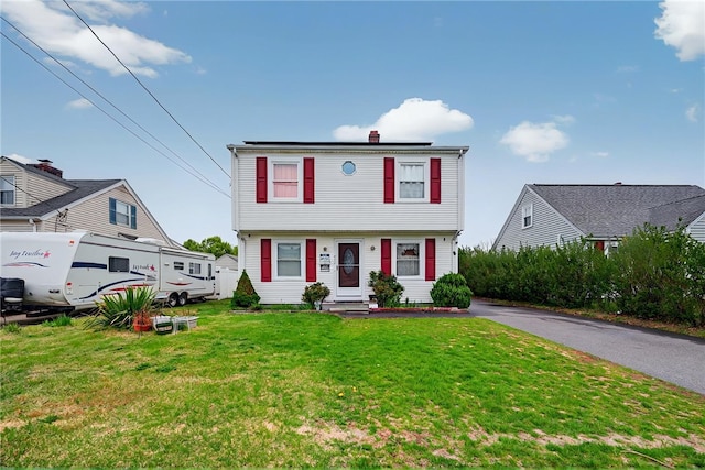 colonial-style house with a chimney and a front yard