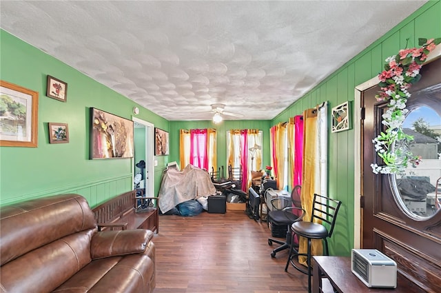 living area featuring a decorative wall, a textured ceiling, wood finished floors, and a ceiling fan