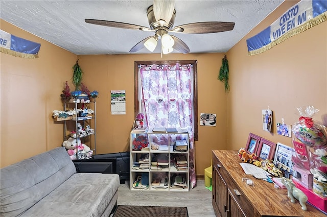 sitting room featuring light wood finished floors, ceiling fan, and a textured ceiling