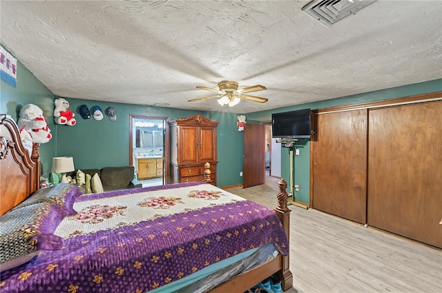 bedroom with connected bathroom, light wood-type flooring, visible vents, and ceiling fan