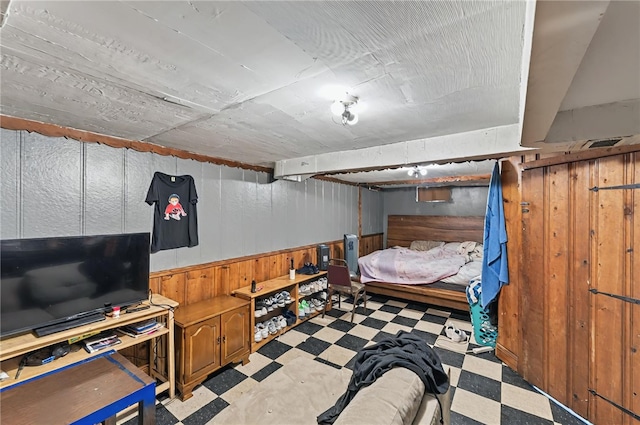 bedroom featuring tile patterned floors, wooden walls, and a wainscoted wall