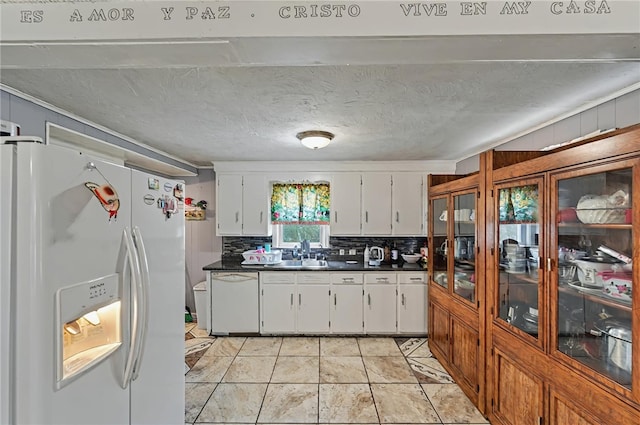 kitchen featuring a sink, dark countertops, white cabinets, white appliances, and tasteful backsplash