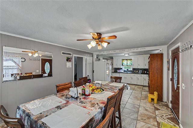 dining area featuring crown molding, a textured ceiling, visible vents, and a ceiling fan