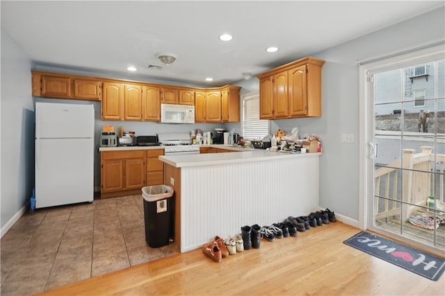 17 Grotto Ave Unit 1, Pawtucket, RI 02860 - kitchen with a peninsula, white appliances, visible vents, light countertops, and baseboards