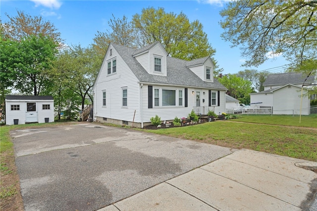 141 Burns St, Providence, RI 02904 - cape cod house featuring a front yard, an outdoor structure, roof with shingles, and fence
