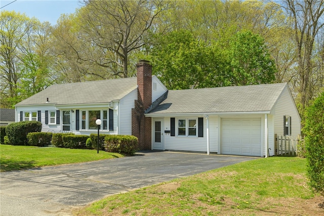 ranch-style house with an attached garage, driveway, a chimney, and a front yard