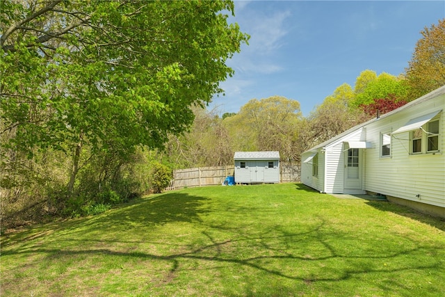 view of yard with a storage shed, an outdoor structure, and fence