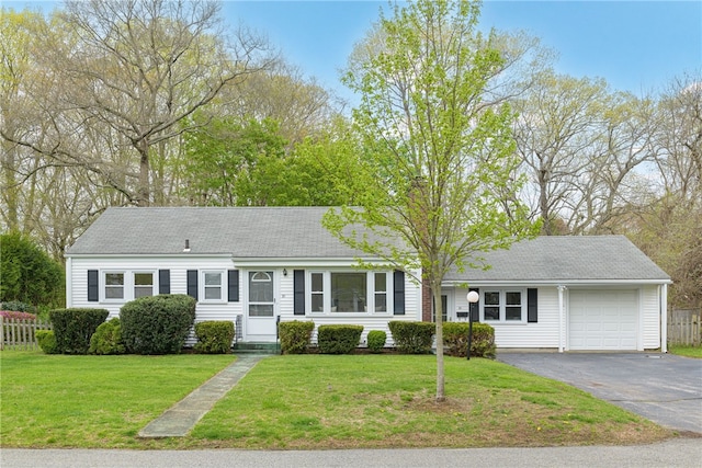 view of front of house with an attached garage, driveway, fence, and a front lawn