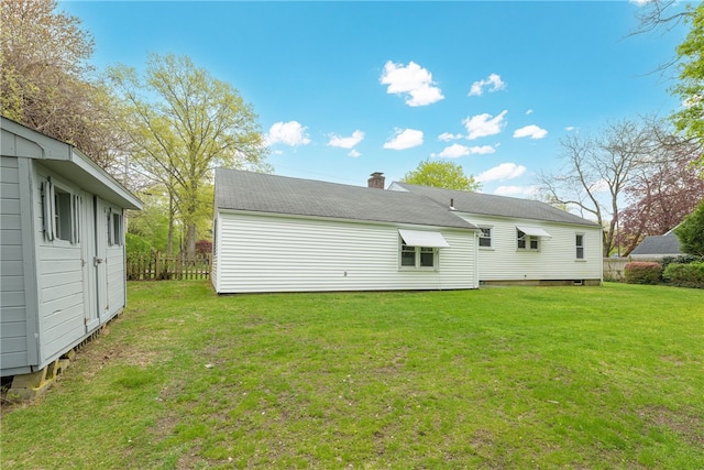 back of property featuring a yard, a chimney, and fence