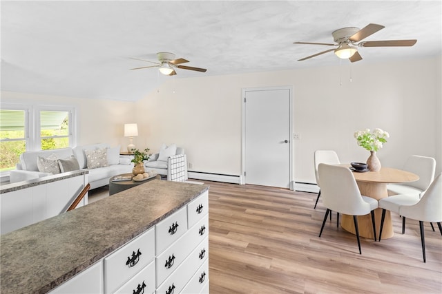 interior space featuring a ceiling fan, light wood finished floors, and a baseboard heating unit
