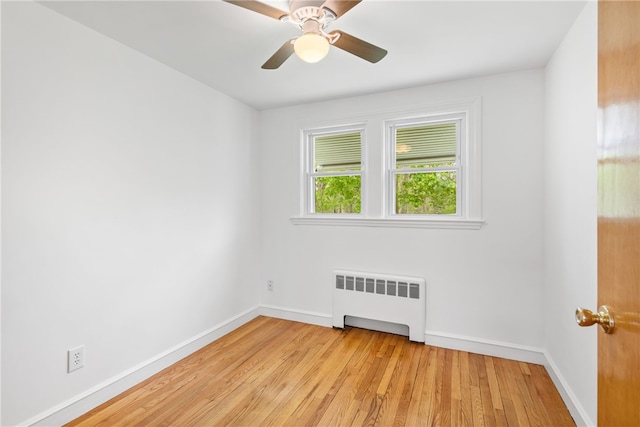 unfurnished room with baseboards, radiator heating unit, light wood-style flooring, and a ceiling fan
