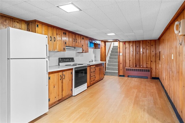 kitchen with radiator, white appliances, light countertops, and light wood-type flooring