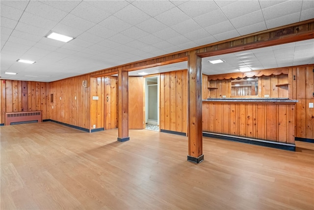 interior space featuring baseboards, radiator, wood walls, and wood finished floors