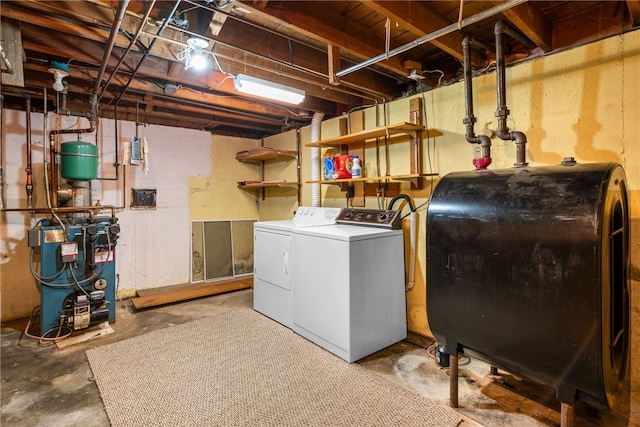 washroom with laundry area, independent washer and dryer, a heating unit, and heating fuel