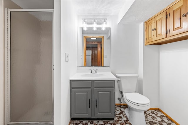 bathroom with a stall shower, vanity, toilet, and baseboards