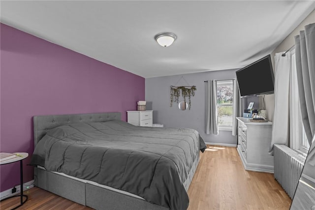 bedroom with radiator heating unit and light wood-style flooring