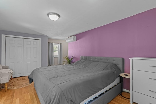 bedroom with a closet, wood finished floors, and an AC wall unit