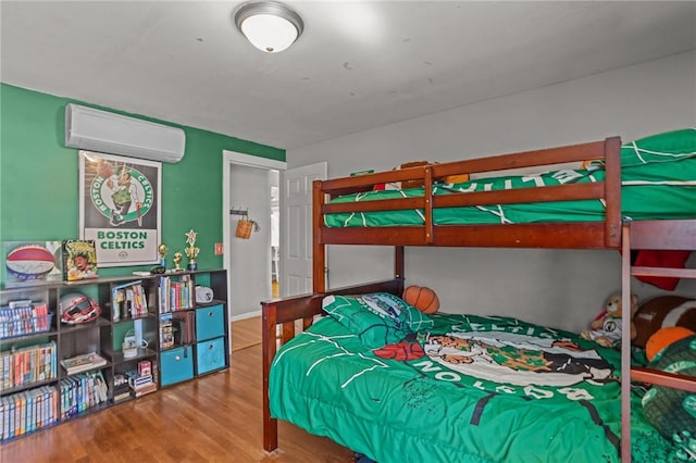 bedroom with an AC wall unit and wood finished floors