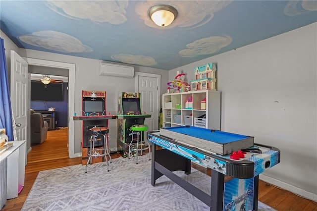 playroom featuring wood finished floors, baseboards, and a wall unit AC