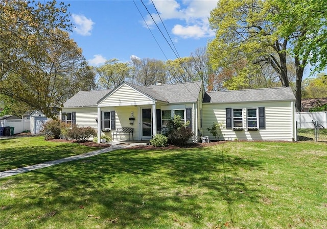 view of front facade featuring roof with shingles, fence, and a front lawn