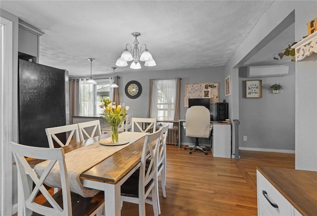 dining room featuring an inviting chandelier, a wall mounted AC, baseboards, and wood finished floors