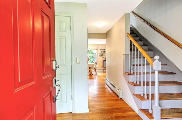 entrance foyer featuring baseboard heating, light wood finished floors, and stairway