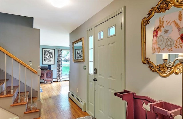 entryway with a baseboard heating unit, light wood-style flooring, stairway, and a wood stove
