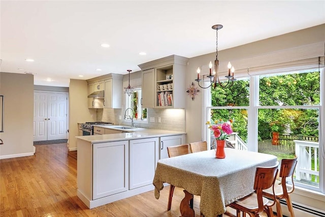 kitchen with high end stove, a sink, light countertops, under cabinet range hood, and open shelves