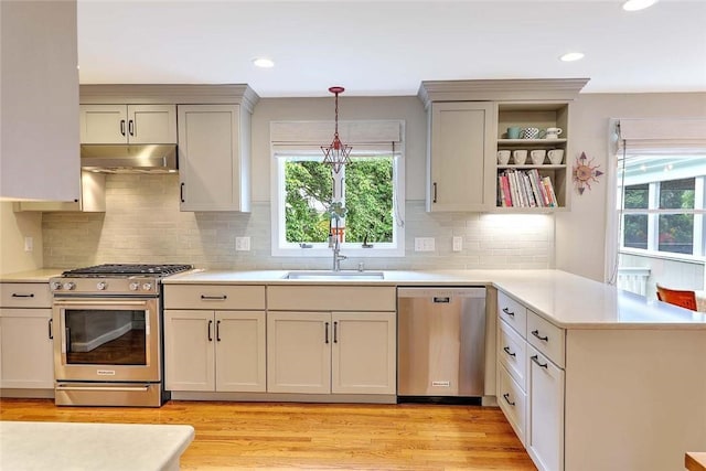 kitchen featuring stainless steel appliances, under cabinet range hood, a peninsula, light countertops, and light wood-style floors